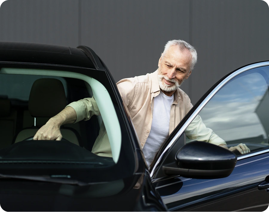 Man entering a black car, looking inside.
